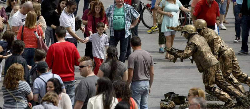 Los turistas caminan entre las 'estatuas vivientes' de Puerta del Sol, Madrid. España acoge visitantes de Reino Unido, Francia, Estados Unidos, Alemania, Italia, América Latina y Asia. Foto: Dani Pozo/ AFP