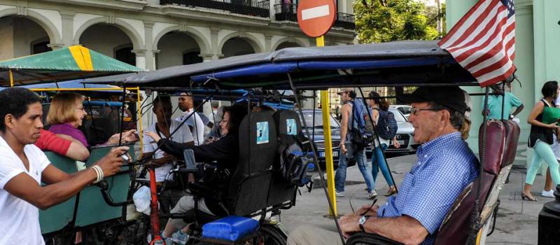 Un taxi de bicicleta con una bandera de Estados Unidos lleva a los turistas en una calle de La Habana. Foto: AFP